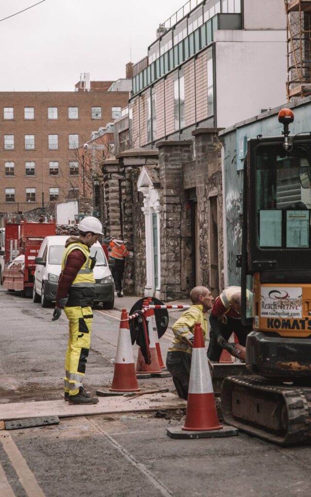 Construction workers wearing safety gear conducting road maintenance in Dublin, Ireland.
